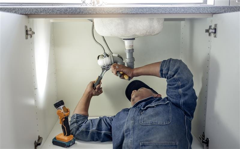Plumber repairing pipes beneath a bathroom sink in Mountain View